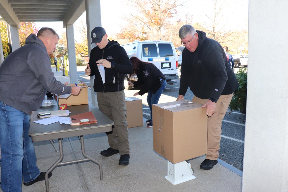 Hampshire Deputy Sheriff Dave Fenton weighs boxes at Saturday's drug collection event.]